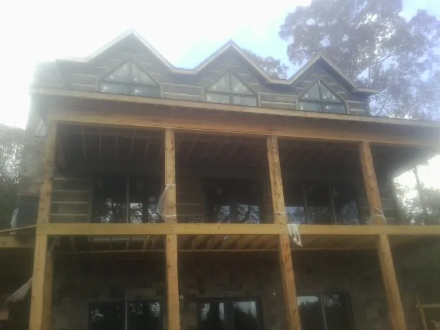 Dormers and porch framing on a large log home under construction — Roof Coating work by our crew in Mount Carmel