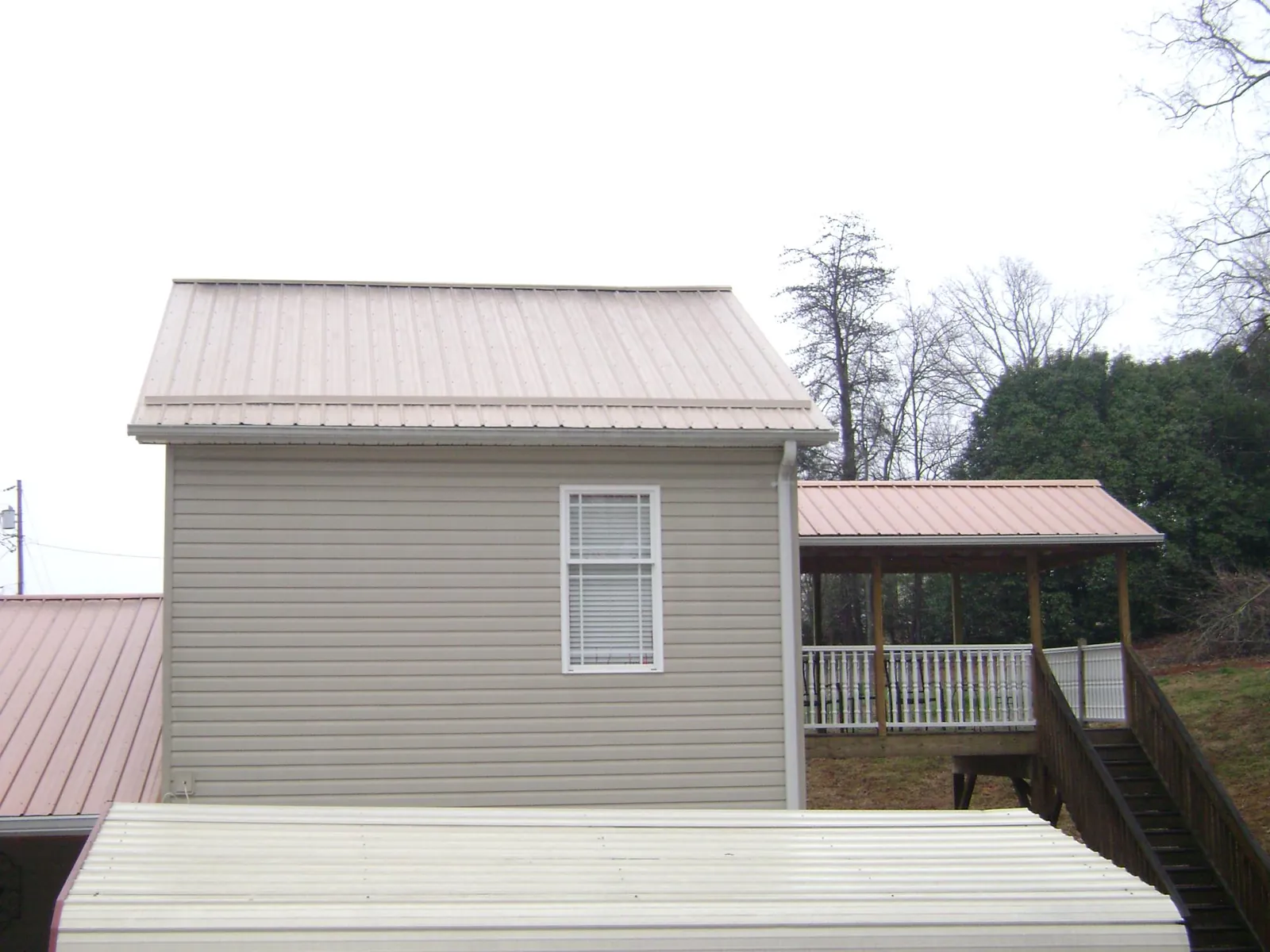 Tan metal roofs on a two story addition and attached porch, from a Roof Replacement job in Mount Carmel